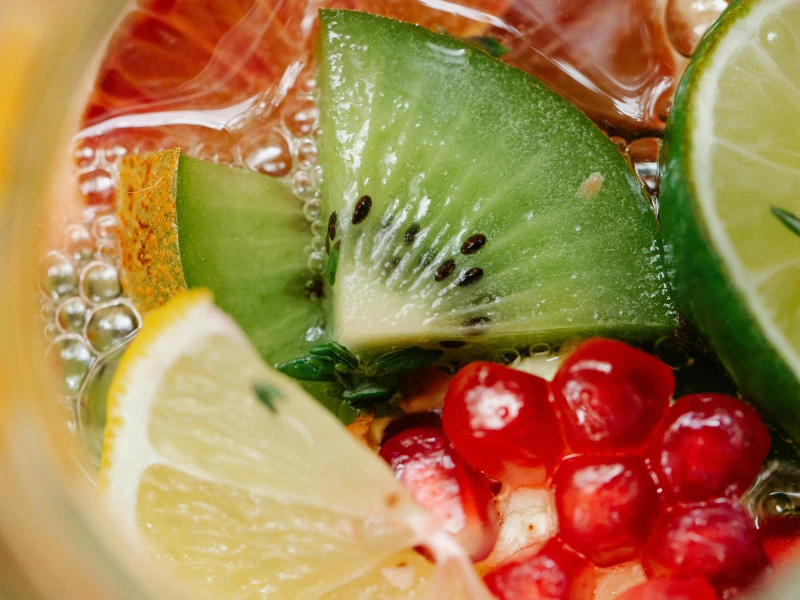 Close-up of fresh fruits in a functional beverage, including kiwi, lime, lemon, and pomegranate